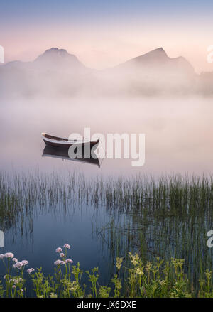 Molto tranquillo la notte d'estate con la barca di legno e la nebbia in Lofoten, Norvegia Foto Stock