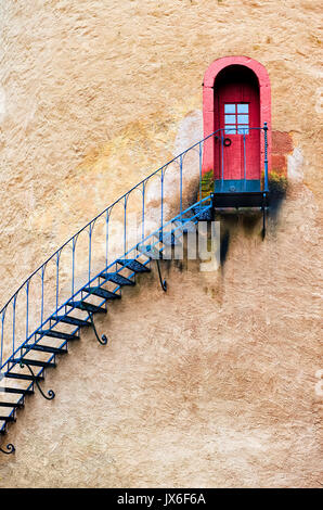 Decorate scala in ferro che conduce fino a una porta rossa della parete in terracotta Foto Stock