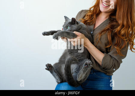 Pretty Woman mentre tiene il suo russo gatto blu in mani. Foto Stock