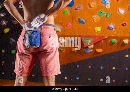 Rocciatore mettendo chalk su mani in piscina palestra di arrampicata Foto Stock