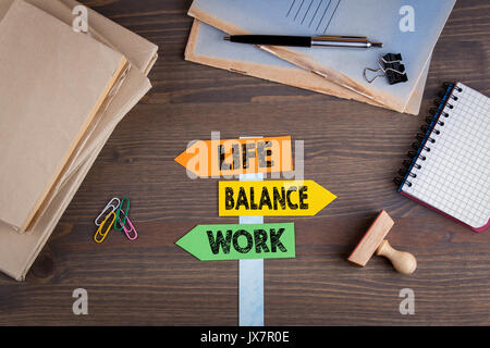 Equilibrio tra lavoro e vita familiare concetto. Orientamento della carta su una scrivania in legno. Foto Stock