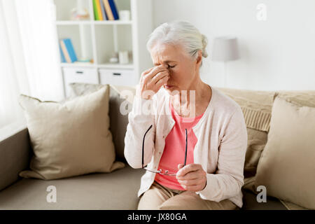 Senior donna con occhiali aventi mal di testa a casa Foto Stock