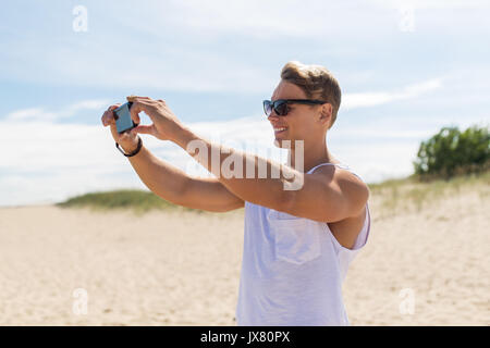 Uomo con lo smartphone a fotografare in estate spiaggia Foto Stock