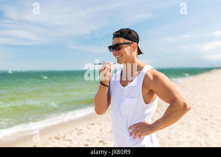 Uomo sorridente chiamando su smartphone in estate spiaggia Foto Stock