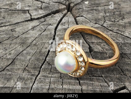 Anello di gioielli con perla su grigio Sfondo legno Foto Stock