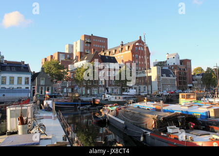 Complesso di appartamenti ex magazzino Albion a Noorderhaven canal a Groningen, Paesi Bassi. Vecchie navi a vela e case galleggianti ormeggiate nella parte anteriore. Foto Stock