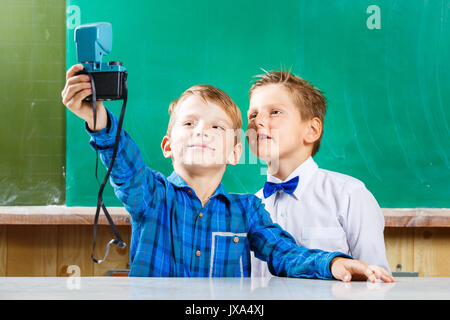 Due compagni di scuola fare selfie a lavagna nella scuola. Si torna a scuola concetto sfondo Foto Stock