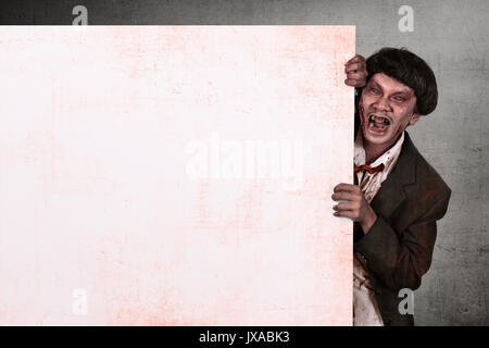 Ritratto di zombie asiatici uomo azienda vuoto banner bianco su sfondo grunge Foto Stock