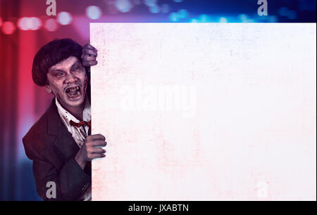 Ritratto di zombie asiatici uomo azienda vuoto banner bianco su sfondo colorato Foto Stock