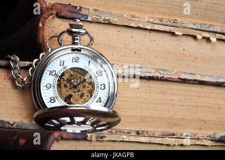 Vintage orologio da tasca con coperchio aperto sullo sfondo con libri antichi Foto Stock