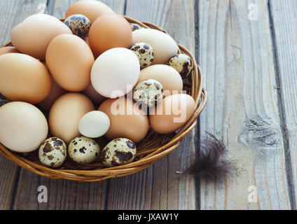 Uova di pollo e quaglie farm in un cesto di vimini. Foto Stock