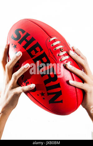 Donna con le mani in mano azienda australiana o AFL Football Foto Stock