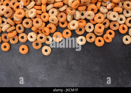 Cerchiature multigrain cereali per la colazione confine con copia spazio su un grigio scuro ardesia Sfondo piastrelle Foto Stock