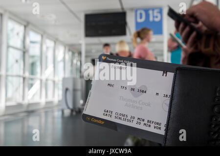 I passeggeri in possesso di carta di imbarco in attesa al gate di partenza a bordo di un volo all'aeroporto di Monaco di Baviera, Germania Foto Stock