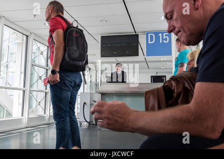 I passeggeri in attesa presso il cancello di partenza a bordo di un volo all'aeroporto di Monaco di Baviera, Germania Foto Stock