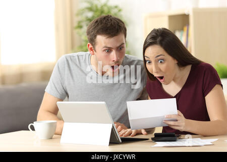 Stupiti matura la lettura insieme una lettera seduti ad una scrivania a casa Foto Stock