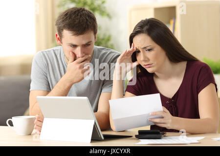 Preoccupato per il giovane la lettura insieme una lettera seduti ad una scrivania a casa Foto Stock