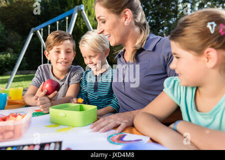 La mamma di pittura con le foto dei loro bambini e durante la pausa pranzo Foto Stock