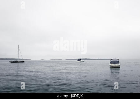 3 barche in acqua tra Sag Harbor e Shelter Island su una nebbia, giornata grigia negli Hamptons, NY. Foto Stock