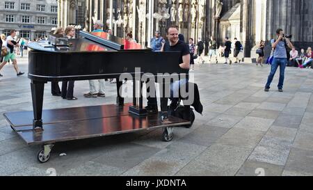 L'uomo gioca su un pianoforte in zona pedonale di fronte la Cattedrale di Colonia entrata principale Foto Stock