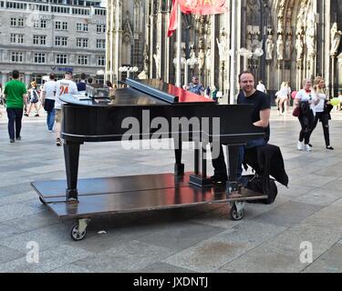 L'uomo gioca su un pianoforte in zona pedonale di fronte la Cattedrale di Colonia entrata principale Foto Stock