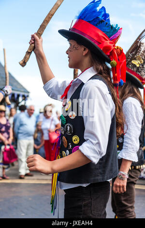 Early teen ragazza adolescente in tradizionale Morris costume ballerino ballando con Dead Horse Morris fianco a Broadstairs Settimana della musica folk. Close up, tenendo palo di legno e indossa cappello nero con fascia di rosso e di blu piume. Foto Stock