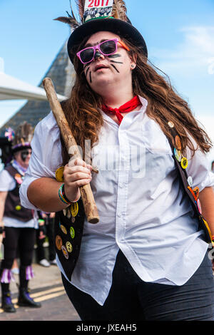 Le giovani donne, nella sua 20s, folk ballerino, ballando con Morris lato, Dead Horse Morris, durante la Broadstairs Settimana della musica folk. Indossare occhiali da sole e cappello nero con piuma e tenendo un pole mentre balli. Foto Stock