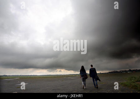 Berlino, Germania. 16 Ago, 2017. I camminatori sotto la pioggia scure nuvole all'ex aeroporto di Tempelhof di Berlino, Germania, 16 agosto 2017. Foto: Wolfgang Kumm/dpa/Alamy Live News Foto Stock