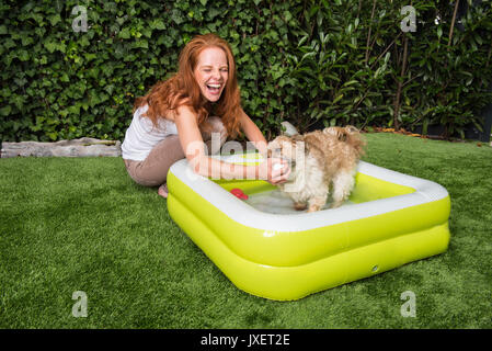 Bellissimi i capelli rossi donna gioca con il suo cane in giardino Foto Stock
