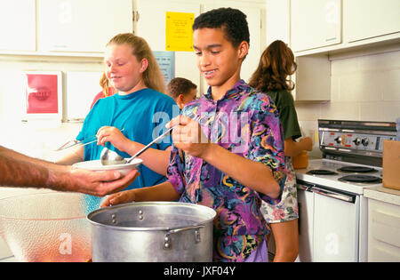 La diversità etnica diverse multi giovani che serve pasti a chi è nel bisogno chiesa soup kitchen distribuendo cibo bambini aiutando © Myrleen Pearson Foto Stock