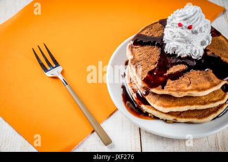 Idee per colazione per bambini, tratta di rendimento di grazie e di Halloween. Frittelle con salsa di cioccolato e panna montata in forma di un fantasma. Su un wh Foto Stock