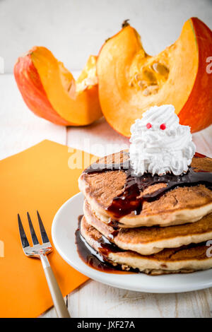 Idee per colazione per bambini, tratta di rendimento di grazie e di Halloween. Frittelle con salsa di cioccolato e panna montata in forma di un fantasma. Su un wh Foto Stock