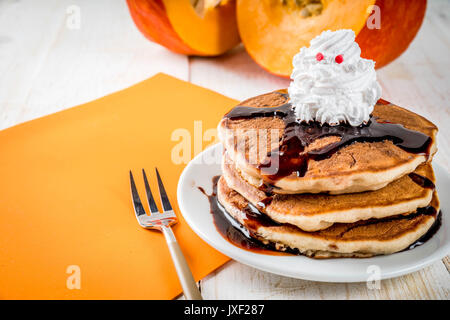 Idee per colazione per bambini, tratta di rendimento di grazie e di Halloween. Frittelle con salsa di cioccolato e panna montata in forma di un fantasma. Su un wh Foto Stock