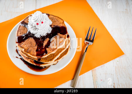 Idee per colazione per bambini, tratta di rendimento di grazie e di Halloween. Frittelle con salsa di cioccolato e panna montata in forma di un fantasma. Su un wh Foto Stock