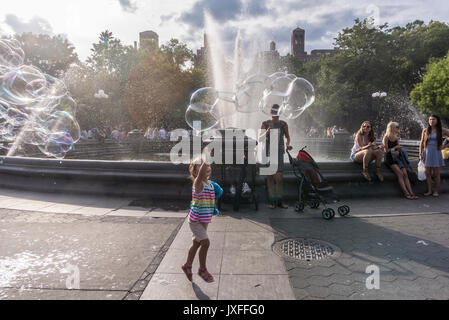 New york, ny, Stati Uniti d'America - 13 agosto 2017 - una giovane ragazza insegue uno spruzzo di spray di bolla in una calda giornata estiva in Washington Square Park in Greenwich village credit: ©stacy rosenstock walsh Foto Stock