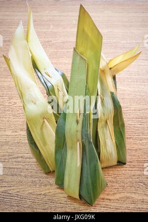 Thai dessert tradizionale, tailandese Cibo dolce avvolti in foglie di banana contenitore su di un tavolo di legno. Foto Stock