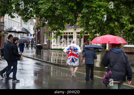 Molto giorno piovoso nel centro di York, indicato con ombrelloni e un uomo in un unione bandiera giacca a vento poncho Foto Stock