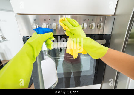 Donna mano guanto che indossa la pulizia del forno in cucina a casa Foto Stock