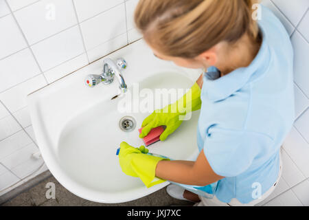 Elevato angolo di visione della donna la pulizia del bacino del bagno Foto Stock