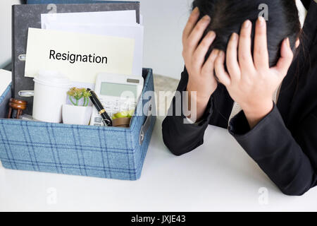 Tristezza bella femmina lavoratore di ufficio è sparato imballaggio oggetti personali seduto sulla scrivania sensazione sconvolto e pensare in futuro posto di lavoro Foto Stock