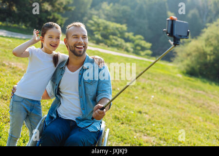 Padre in una sedia a rotelle e la figlia in posa per una selfie Foto Stock