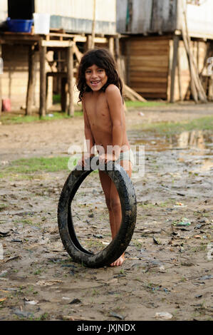 Il Perù, Amazzonia - 23 giugno: Giovani Native American giocando con il pneumatico nel suo villaggio nella giungla amazzonica nel giugno 23, 2012 Foto Stock