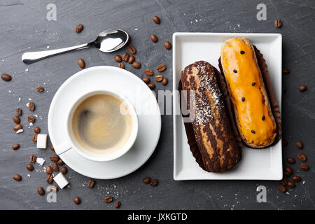 Tazza di caffè con il francese eclairs sulla pietra scura sullo sfondo Foto Stock