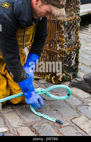 Fisherman la giunzione delle funi nuove per reti da pesca. Porto di Pittenweem presso il fronte mare. Fife Scozia UK Foto Stock