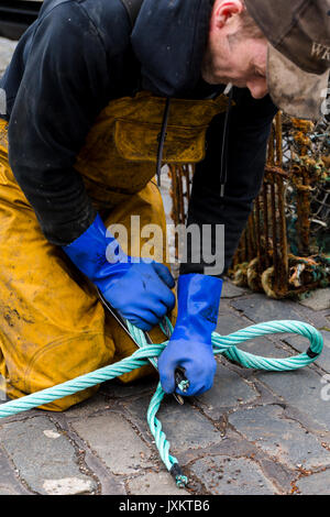 Fisherman la giunzione delle funi nuove per reti da pesca. Porto di Pittenweem presso il fronte mare. Fife Scozia UK Foto Stock