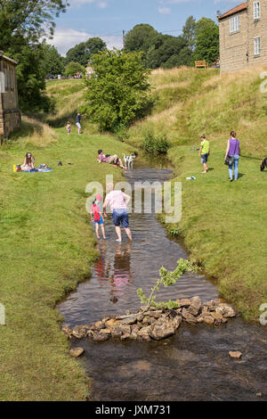 I turisti in un flusso a Hutton Le Hole Village, North York Moors, nello Yorkshire, Inghilterra, Regno Unito Foto Stock