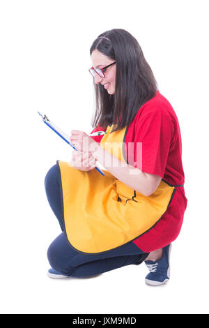 Ipermercato venditore verifica i prodotti sul ripiano inferiore e la scrittura su Appunti Foto Stock