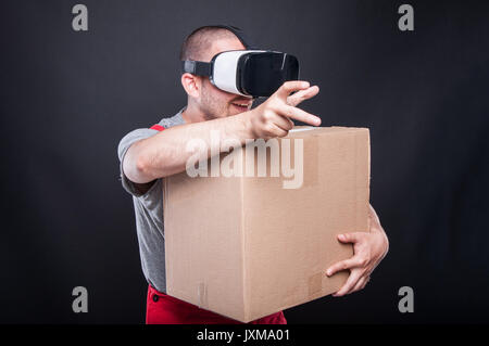 Mover guy scatola di contenimento afferrando qualcosa indossando occhiali vr su sfondo nero Foto Stock