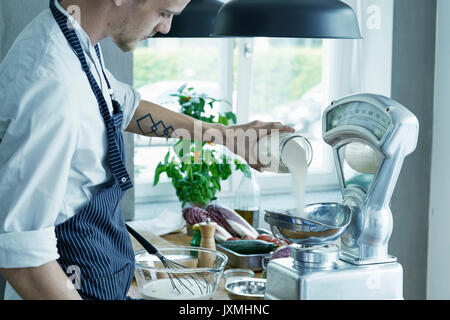 Lo chef maschio, ingredienti di pesatura su scale vintage Foto Stock