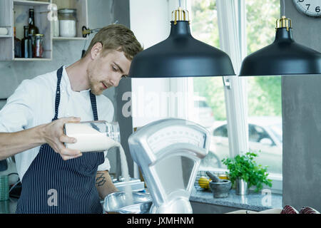 Lo Chef versando gli ingredienti in scale vintage Foto Stock